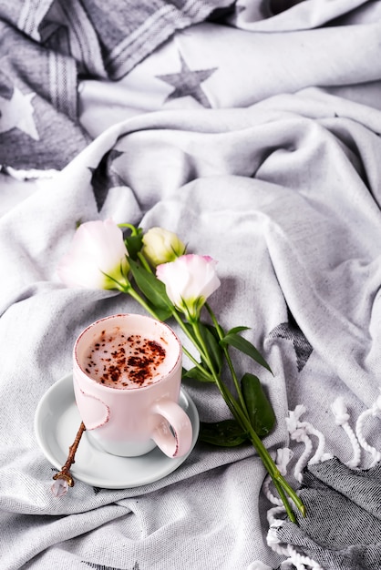 Met een kopje koffie met chocolade, bloemen eustoma op deken in bed.