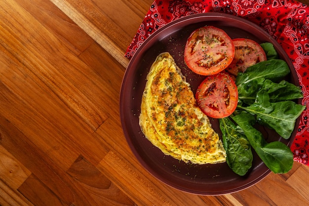 Foto met een omelet en salade van gesneden tomaten en arugula