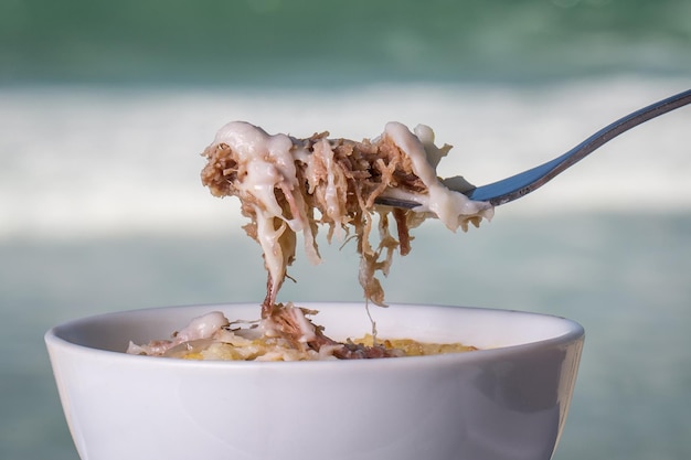 met een vork van gedroogd vlees cassave en kaas. Braziliaans eten genaamd Escondidinho de Carne Seca