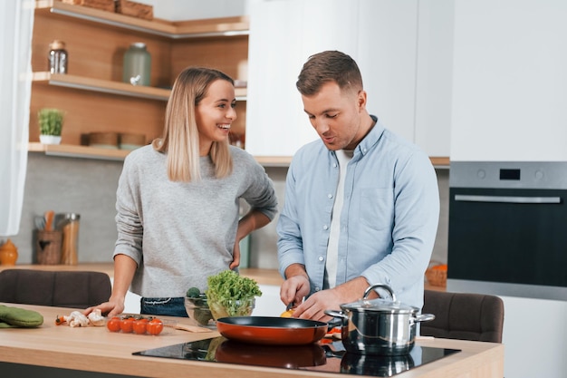 Met elkaar praten Echtpaar bereiden van voedsel thuis op de moderne keuken