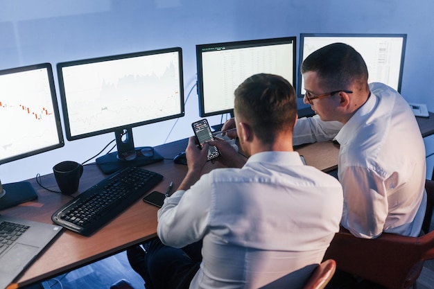 Foto met elkaar praten twee beurshandelaren aan het werk op kantoor met beurstechnologie