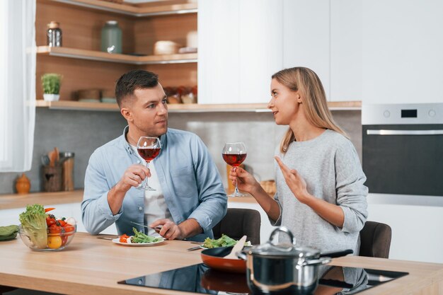 Met glazen wijn Paar bereiden van voedsel thuis op de moderne keuken