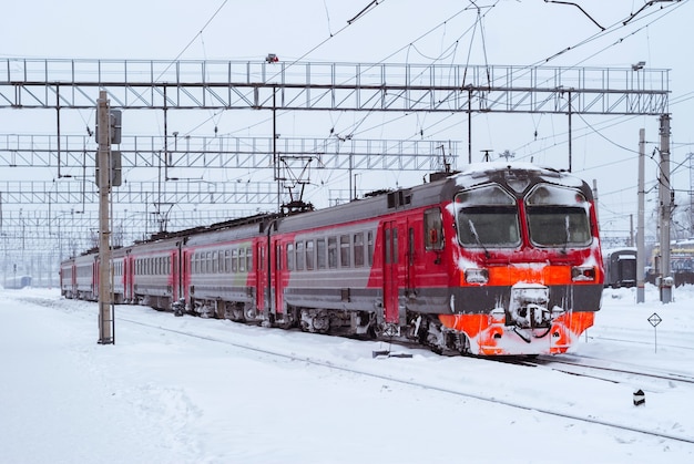 Met ijs bedekte elektrische trein met treinstellen op een spoorwegknooppunt in de winter