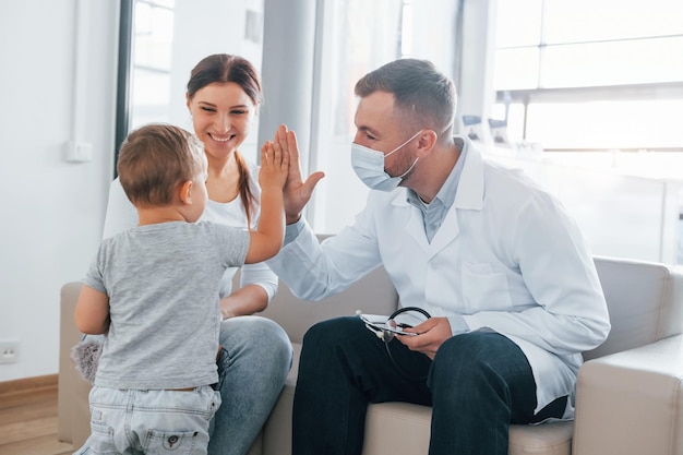 Met kleine jongen Twee dokters in witte jassen werken samen in de kliniek