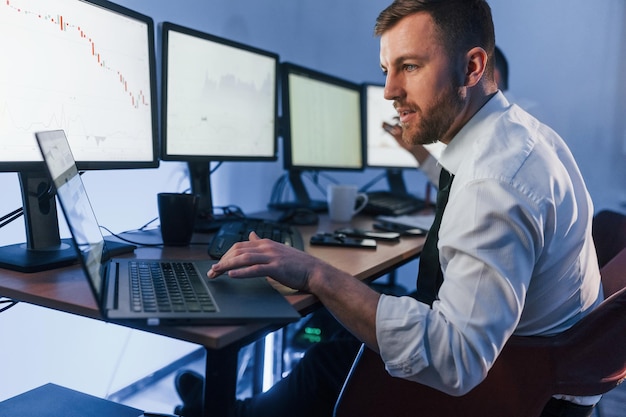 Met laptop op tafel Twee beurshandelaren aan het werk op kantoor met uitwisselingstechnologie