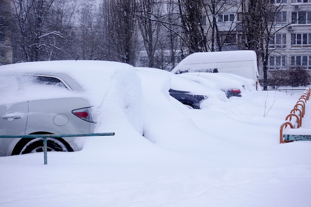 Met sneeuw bedekte auto's op een parkeerplaats in de stad