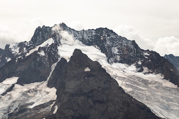 Met sneeuw bedekte bergketen in de wolken. Kaukasus, Rusland.