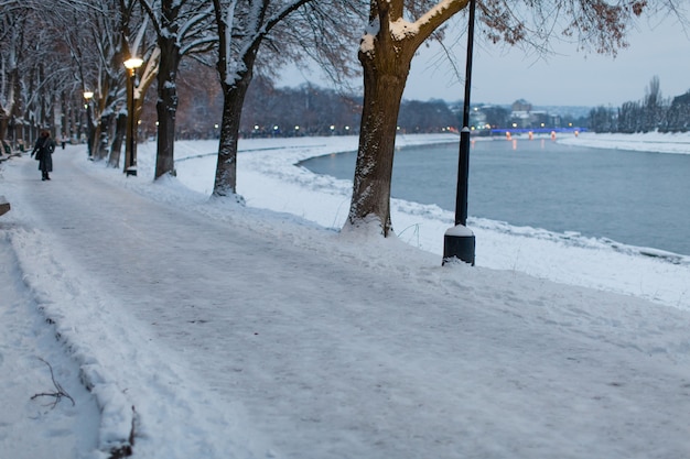 Met sneeuw bedekte dijk in de stad van de avond. Prachtig winterlandschap