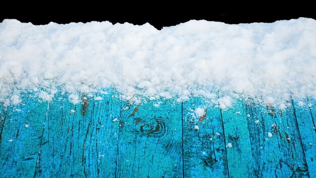 Met sneeuw bedekte oude blauwe planken op een zwarte geïsoleerde achtergrond, winterachtergrond voor ontwerp