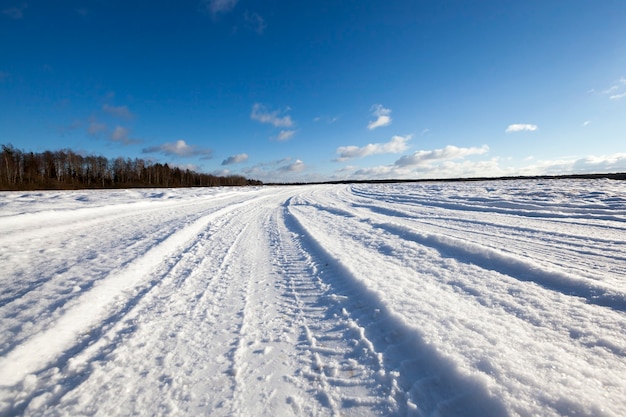 Met sneeuw bedekte weg in het winterseizoen. Zichtbare sporen van de auto. Hemel op de achtergrond