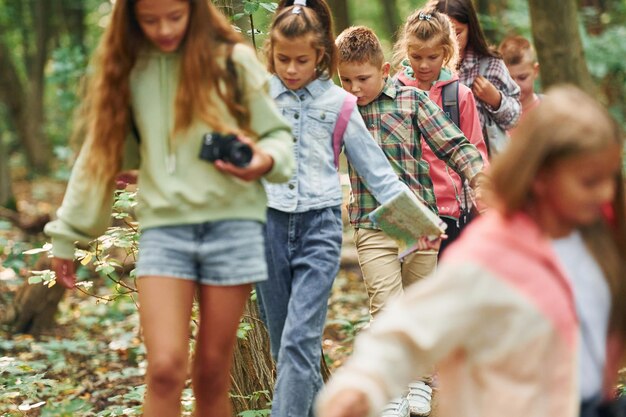 Foto met toeristische uitrusting kinderen in groen bos op zomerdag samen