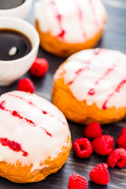 Met verse frambozengelei gevulde donuts met witte glazuur erop.