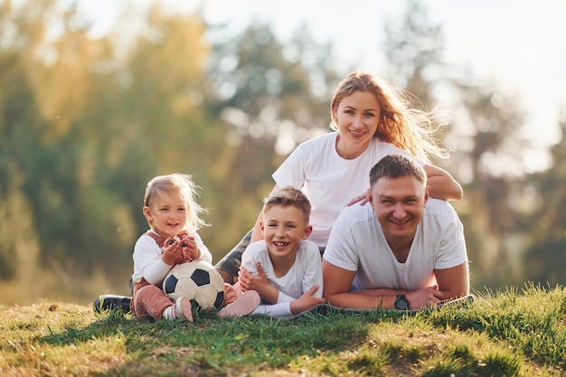 Met voetbal Gelukkige familie die buiten in de buurt van het bos ligt Met dochter en zoon