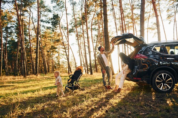 Met zwart gekleurde auto Gelukkig gezin van vader moeder en dochtertje is in het bos