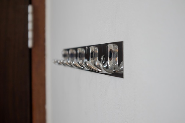 Metaal of roestvrij staal hanger op witte muur Zilveren haakjes achter de deur