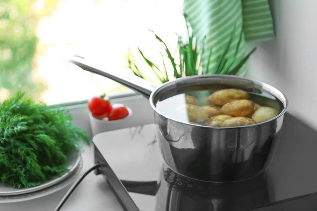 Metaalpot met aardappel op inductiekookplaat in keuken