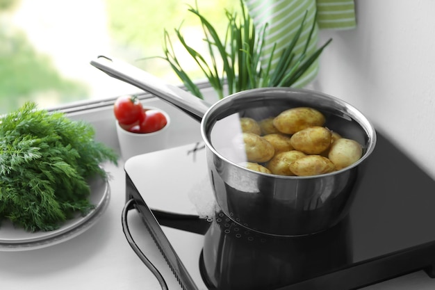 Metaalpot met aardappel op inductiekookplaat in keuken