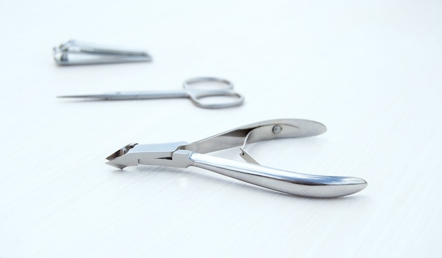 metal accessories for manicure on a white wooden background