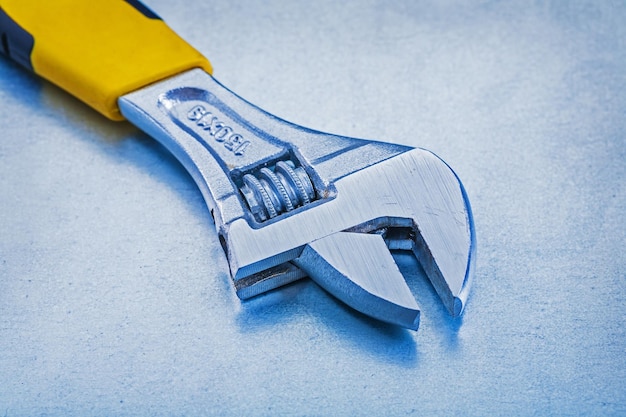 Metal adjustable spanner on metallic background construction concept