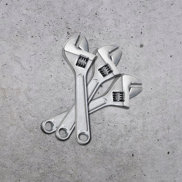 metal adjustable wrenches on a cement background top view