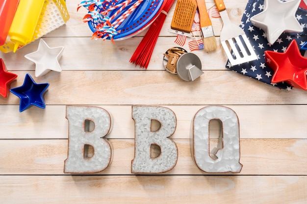 Metal BBQ sign with BBQ cooking tools on a wood background.