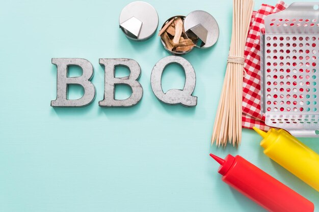 Metal BBQ sign with grilling tools on blue background.