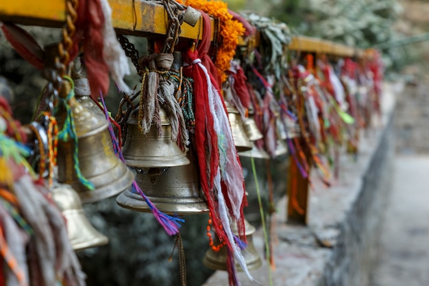 Photo metal bells hang on chains in a hindu temple