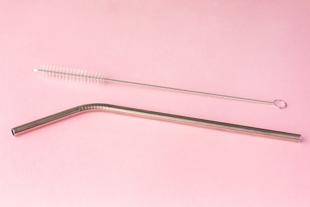 Metal, bendy drinking straw and steel cleaning brush on pink