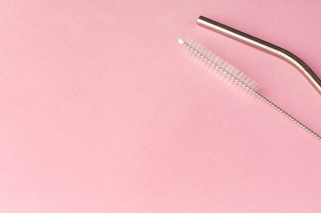 Metal, bendy drinking straw and steel cleaning brush on pink