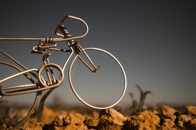 A metal bicycle on a rock with a dark background.