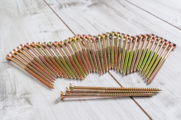 Metal big Screws organized in a row on wooden background. Close up stock photo.