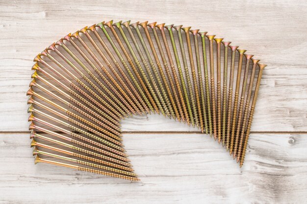 Metal big Screws organized in a row on wooden background. Flat lay top view with a copyspace for text. Stock photo