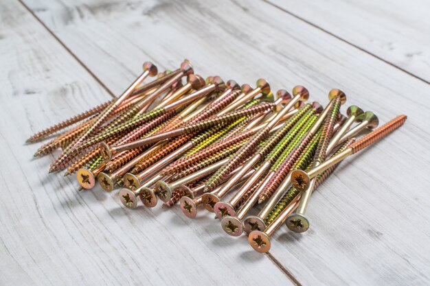 Metal big Screws on wooden background. Close up stock photo.