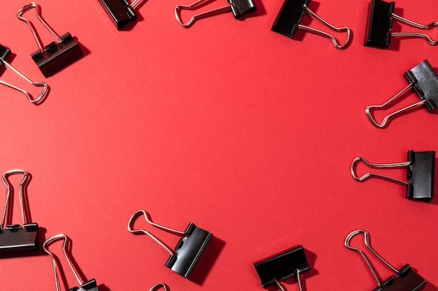 Metal black binder clips on a red background