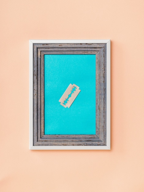 A metal blade in a frame on the blue wall. Minimalism. Contemporary creativity. Collage.