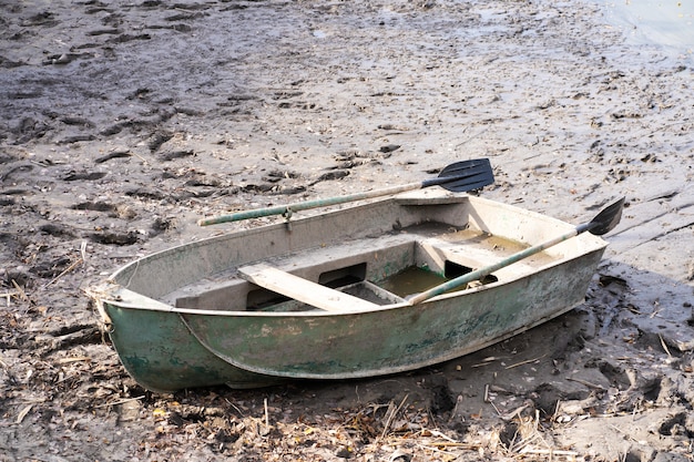 A metal boat with oars on the river bank. Fishing season