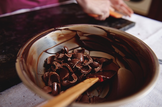 Metal bowl with dark chocolate and cooled melted chocolate mass. Closeup