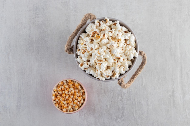 Metal bucket of salted popcorn placed on stone background. 