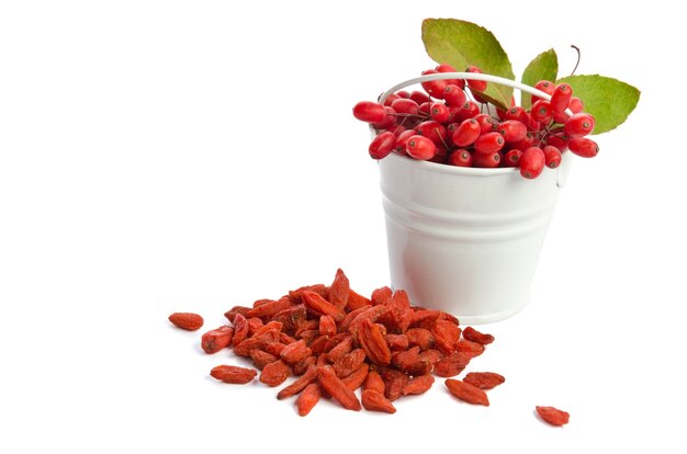 Metal bucket with berberries near heap of goji berries