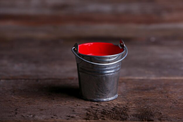 Metal bucket with colorful paint on wooden background