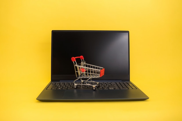 A metal cart with a laptop on a yellow isolated background with space for text.