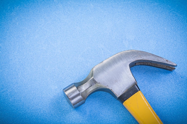 Metal claw hammer on blue background construction concept.