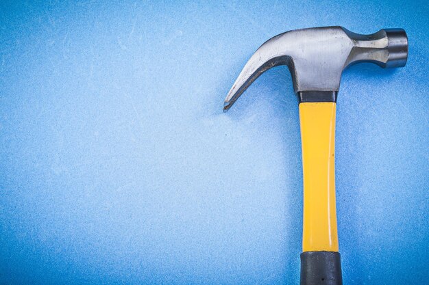 Metal claw hammer on blue background horizontal version construction concept.