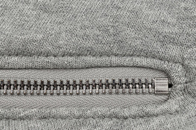 Metal closed zipper in grey knitted textile.