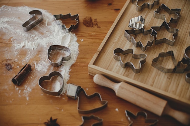 Photo metal cookie cutters rolling pin flour on wooden table for gingerbread cookiesmaking xmas cookies