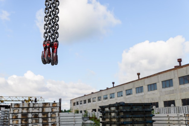 Metal crane hooks against the background of the sky and industrial buildings