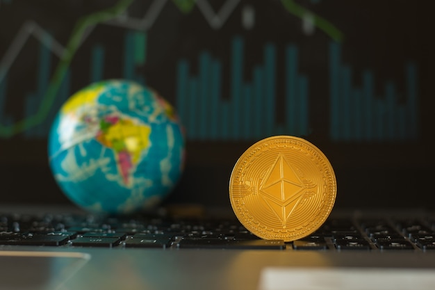 Photo a metal digital coin and a model of the globe on the background of an exchange chart.