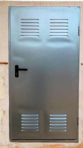 Металлическая дверь серого стального цвета из алюминия крупным планом, дверь закрывает стойки в стене