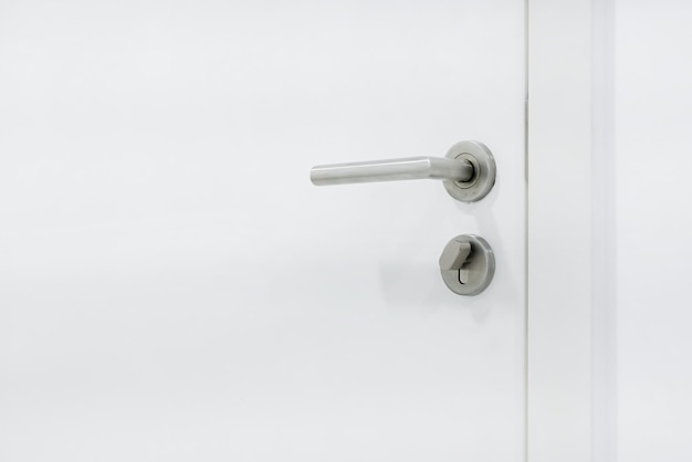 写真 白い木製のドアのロック付きの金属のドアハンドル インテリアドアのドアハンブルを閉じる