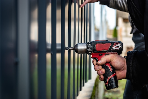 Metal fence installation the worker is screwing the screw into\
the metal fence